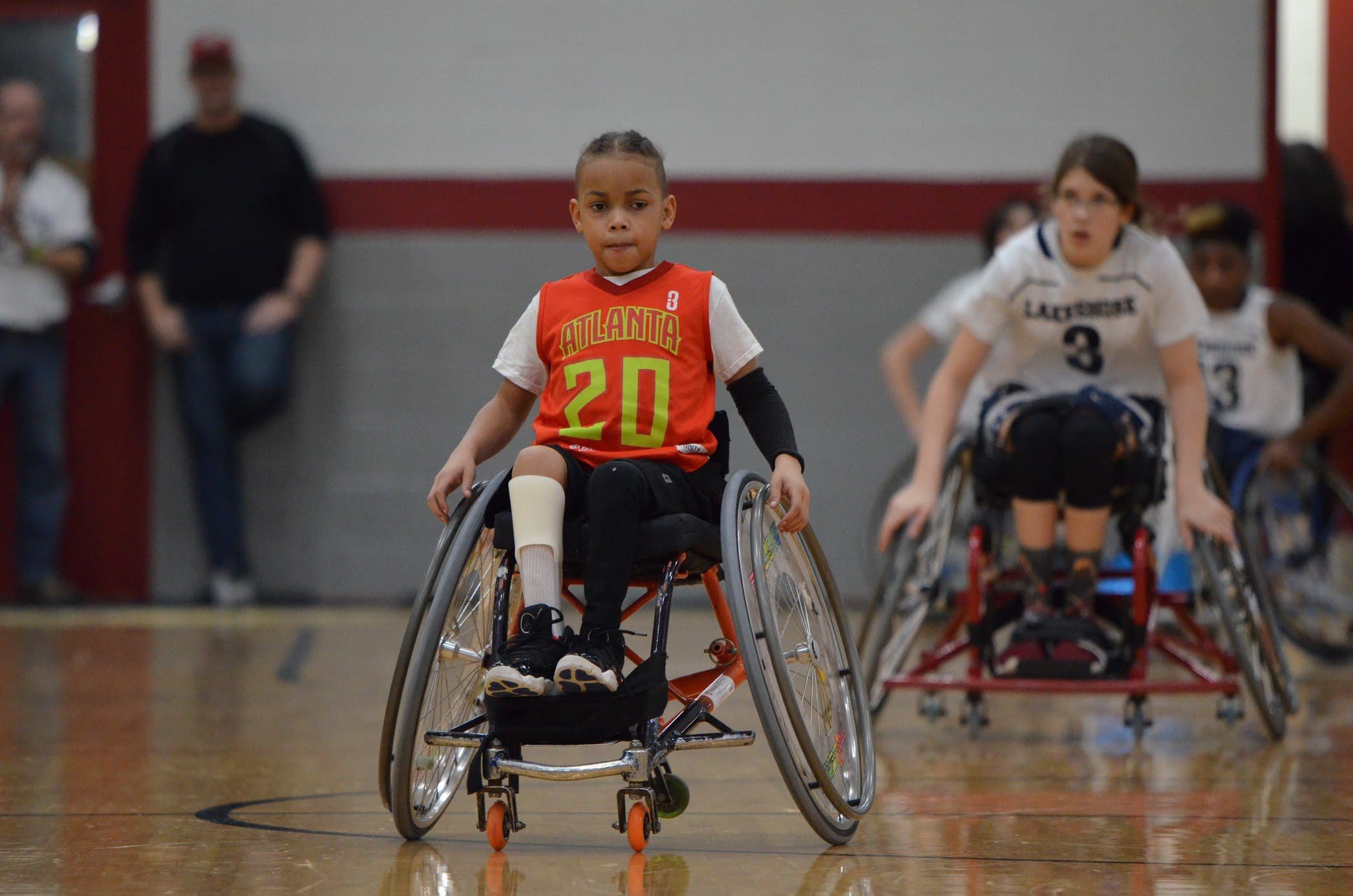 young boy in wheelchair going down the basketball court