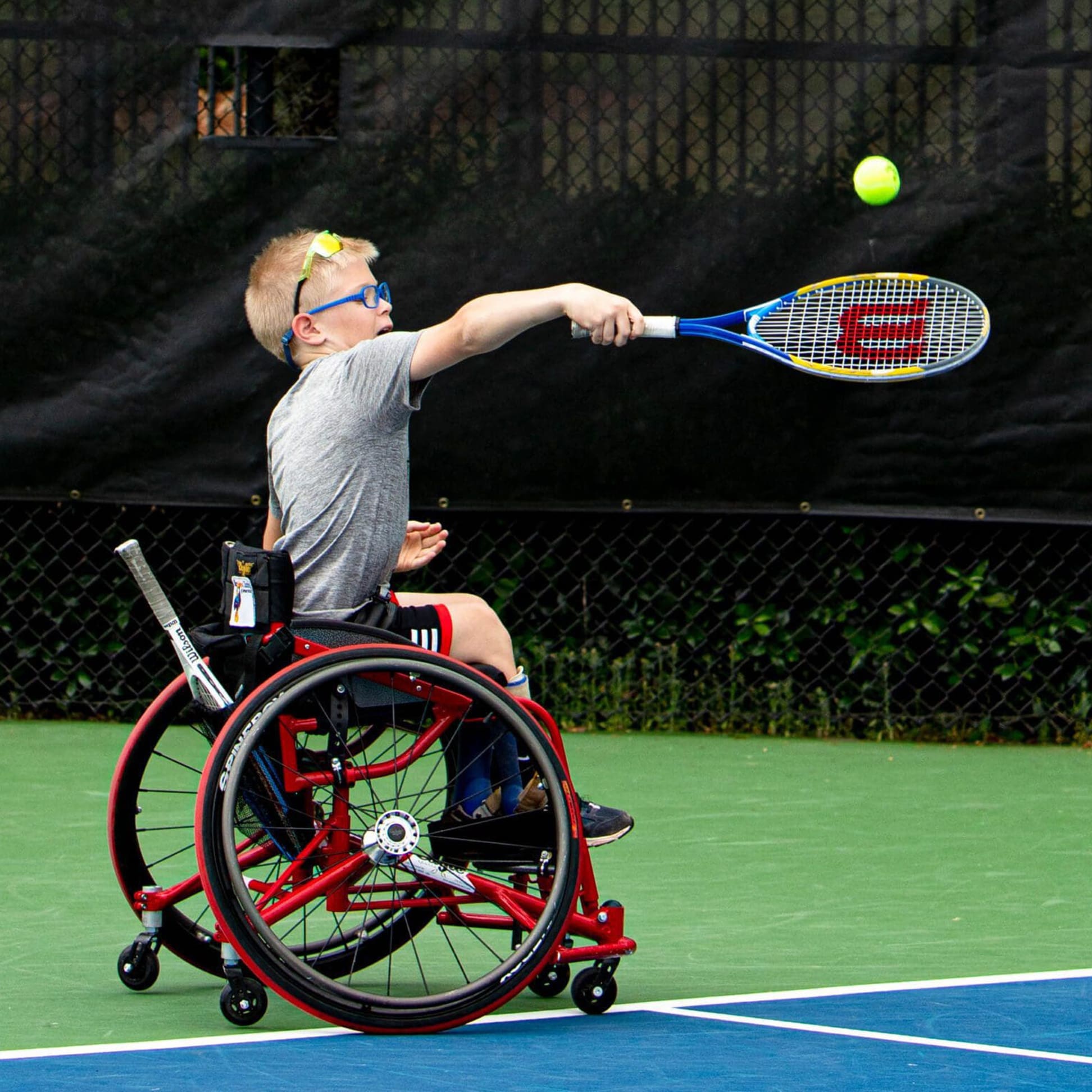 teenage girl hitting a yellow tennis ball with a racket 